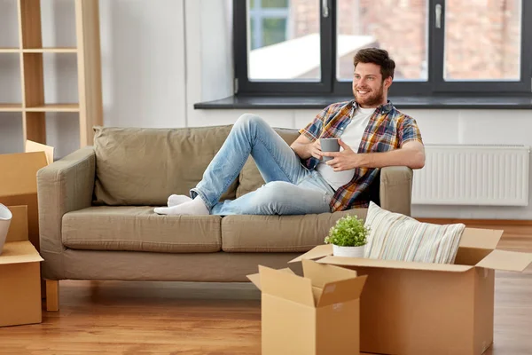 Man with boxes and drinking coffee at new home — Stock Photo, Image