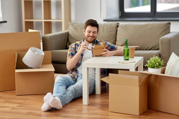 Sonriente hombre comiendo comida para llevar en nuevo hogar —  Fotos de Stock