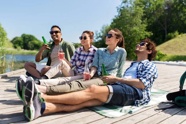 Amici bere birra e sidro sul molo del lago — Foto Stock