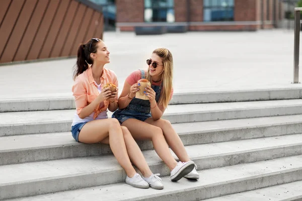 Teenage girls or friends eating burgers outdoors — Stock Photo, Image
