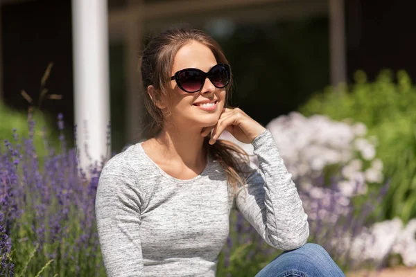 Šťastná mladá žena v slunečních brýlích na letní zahradě — Stock fotografie