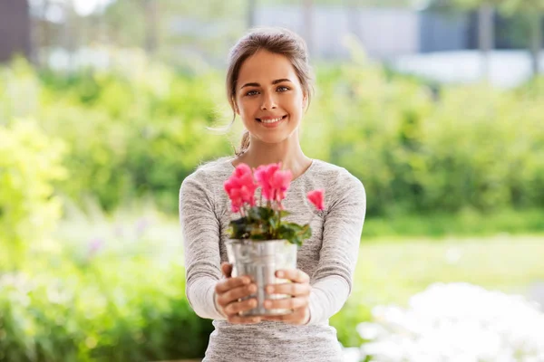Jonge vrouw met Cyclamen bloemen in zomertuin — Stockfoto