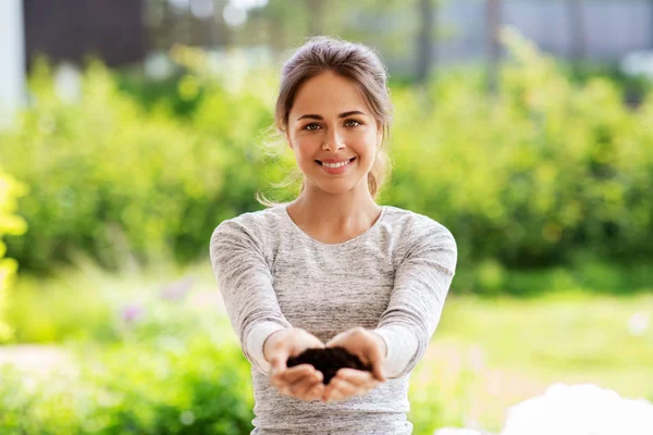 Young woman with handful of soil at summer garden — Stock Photo, Image