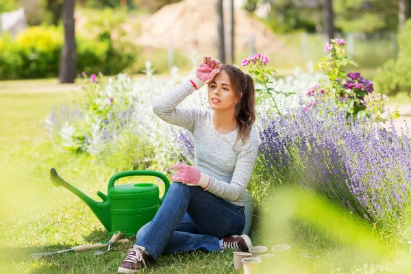 Zmęczona młoda kobieta z narzędziami ogrodowymi w lecie — Zdjęcie stockowe