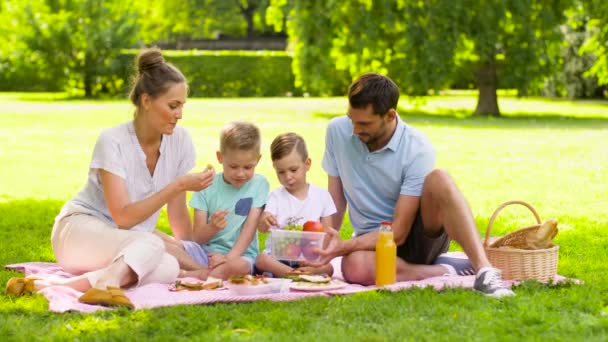 Familia feliz comiendo frutas en el picnic en el parque — Vídeo de stock