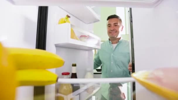 Muž s banány z ledničky doma v kuchyni — Stock video
