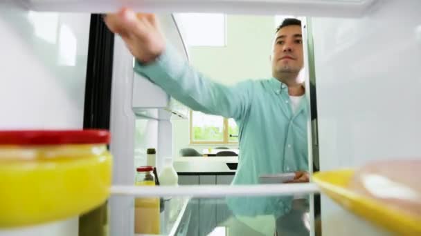 Homem que faz a lista da comida necessária da geladeira — Vídeo de Stock