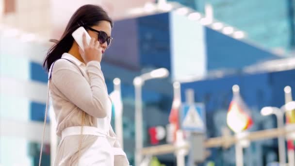 Lachende Aziatische vrouw die op een smartphone belt in de stad — Stockvideo