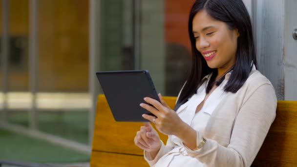 Bankta oturan tablet bilgisayar ile asyalı kadın — Stok video