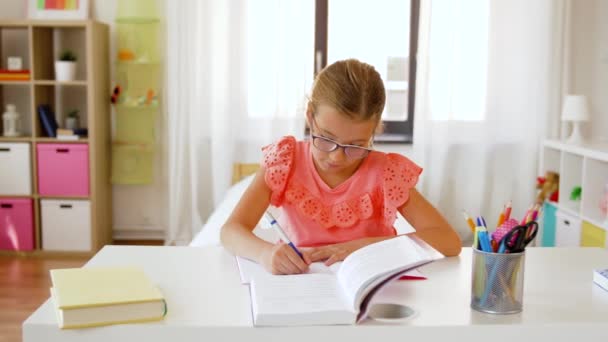 Student meisje met boek schrijven naar notebook thuis — Stockvideo
