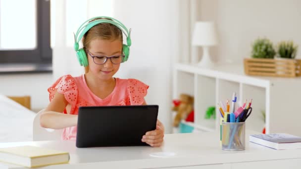 Evde tablet bilgisayarlı kulaklıklı bir kız. — Stok video