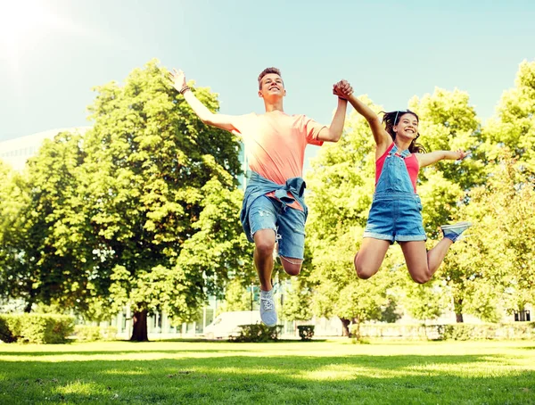 Glad tonåring par hoppar på sommaren park — Stockfoto