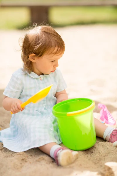 Pequena menina brinca com brinquedos em sandbox — Fotografia de Stock