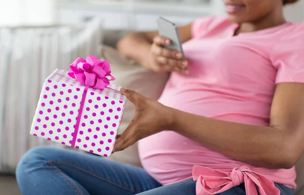 Afrikansk gravid kvinde med smartphone og gave - Stock-foto