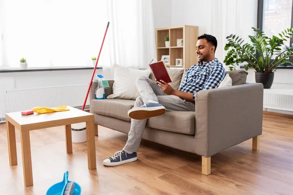 Hombre leyendo libro y descansando después de la limpieza del hogar — Foto de Stock