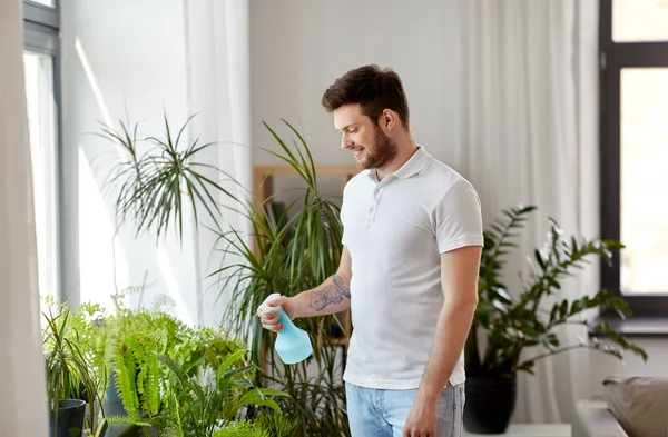 Férfi permetezés szobanövények vízzel otthon — Stock Fotó