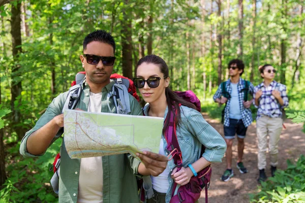 Amis avec carte et sacs à dos randonnée en forêt — Photo