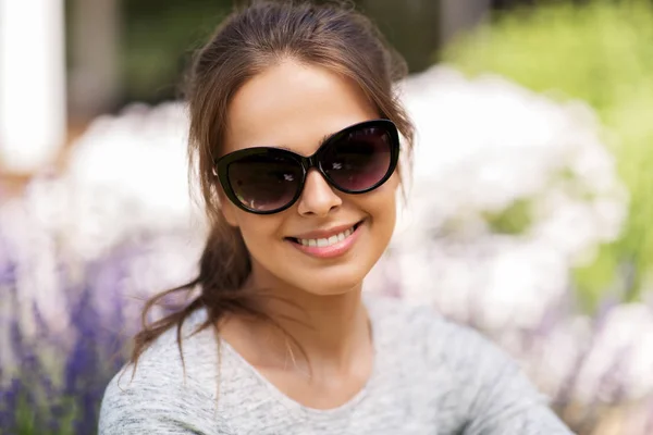 Felice giovane donna in occhiali da sole nel giardino estivo — Foto Stock