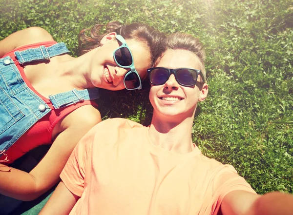 Szczęśliwa para nastoletnich biorąc selfie na trawie lato — Zdjęcie stockowe