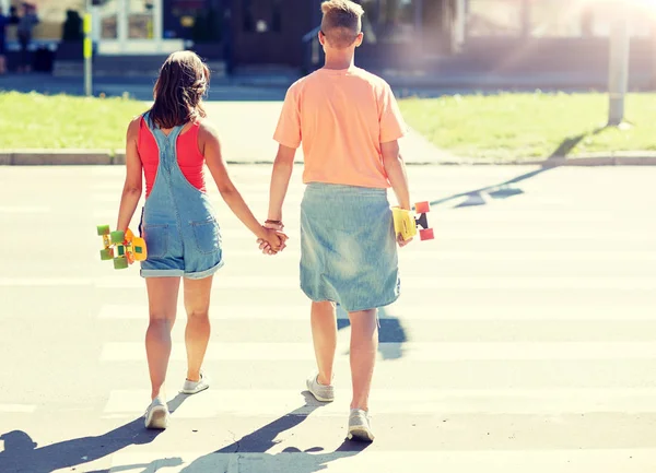 Casal adolescente com skates na travessia da cidade — Fotografia de Stock