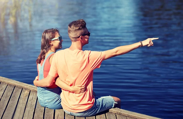 Счастливая пара, указывающая пальцем на летний берег реки — стоковое фото