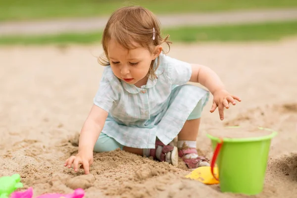 小さな女の子はサンドボックスでおもちゃで遊ぶ — ストック写真