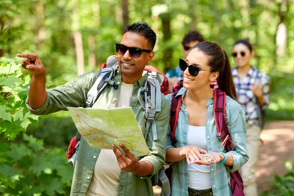 Amigos con mapa y mochilas senderismo en el bosque — Foto de Stock