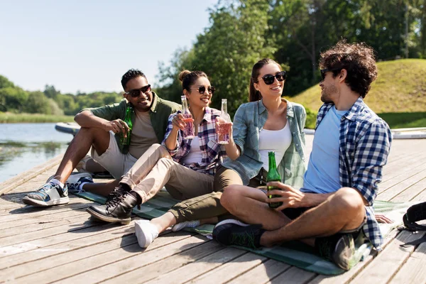 Amici bere birra e sidro sul molo del lago — Foto Stock