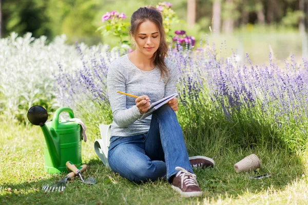 Jonge vrouw schrijven naar notebook in de zomer tuin — Stockfoto