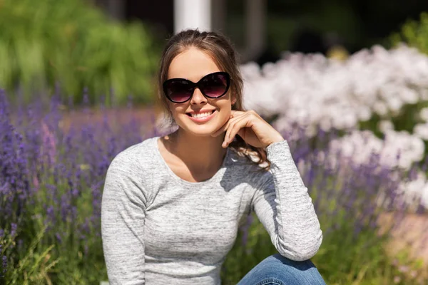 Szczęśliwa młoda kobieta w okularach przeciwsłonecznych w ogrodzie letnim — Zdjęcie stockowe
