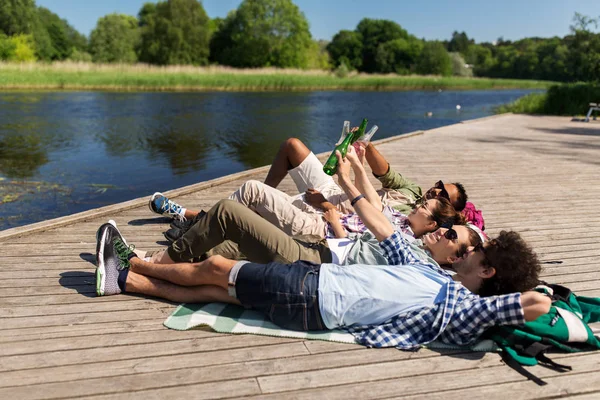 Amici bere birra e sidro sul molo del lago — Foto Stock