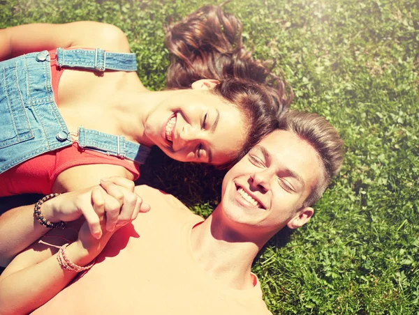 Feliz casal adolescente deitado na grama no verão — Fotografia de Stock