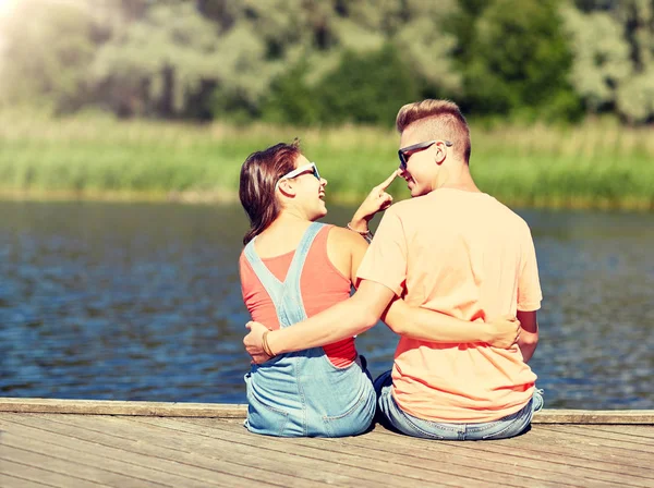 Glückliches Teenie-Paar umarmt sich auf Sommerliegeplatz am Fluss — Stockfoto