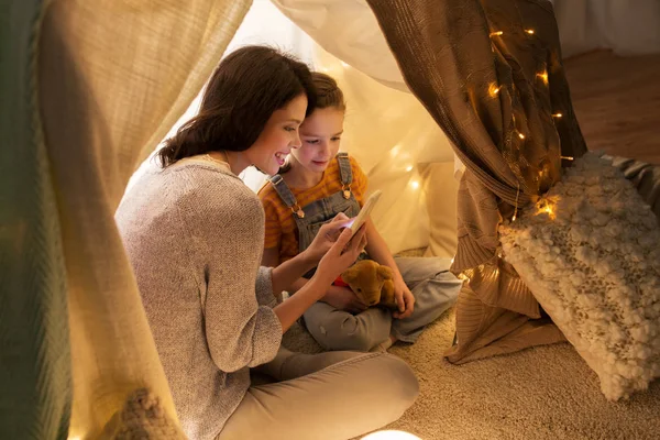 Familia feliz con smartphone en tienda de campaña para niños en casa —  Fotos de Stock