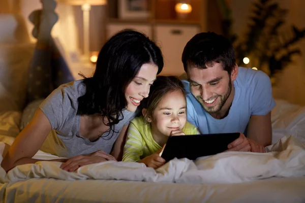 Familj med TabletPC i sängen på natten hemma — Stockfoto