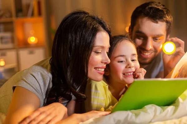 Ευτυχισμένη οικογένεια ανάγνωση βιβλίων στο κρεβάτι τη νύχτα στο σπίτι — Φωτογραφία Αρχείου