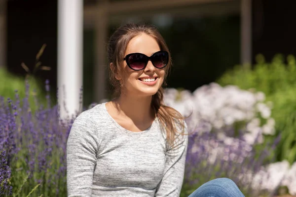 Felice giovane donna in occhiali da sole nel giardino estivo — Foto Stock