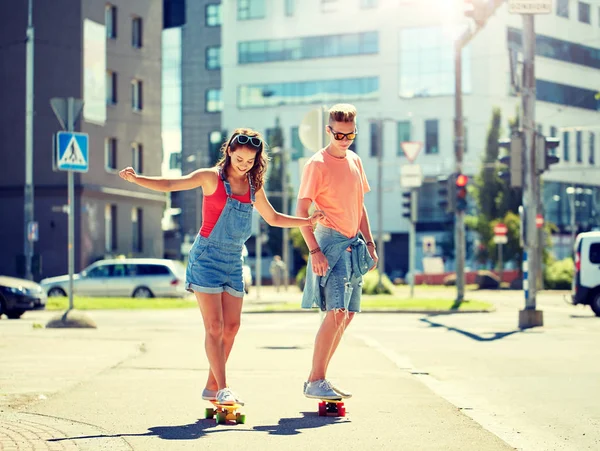 Adolescent couple équitation skateboards sur ville rue — Photo