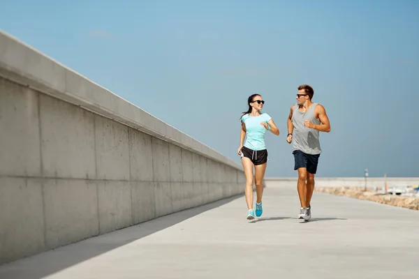 Couple in sports clothes running outdoors — Stock Photo, Image