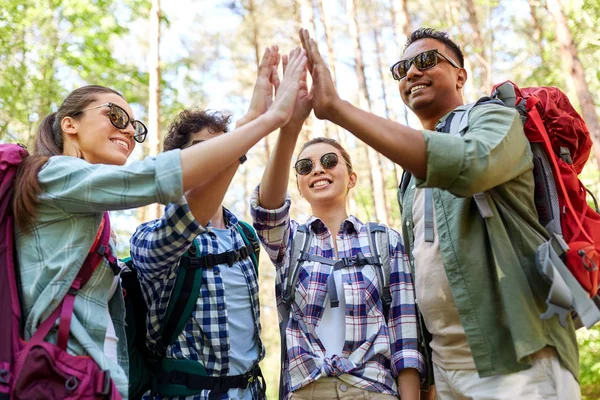 Vänner med ryggsäckar vandring och göra höga fem — Stockfoto