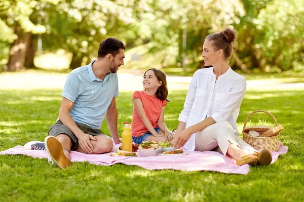 Família feliz fazendo piquenique no parque de verão — Fotografia de Stock