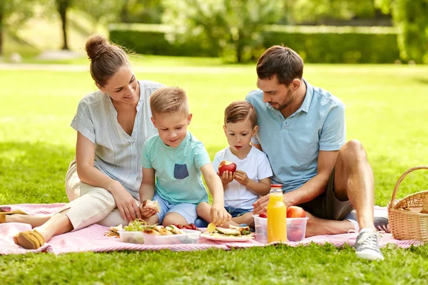 Família feliz fazendo piquenique no parque de verão — Fotografia de Stock