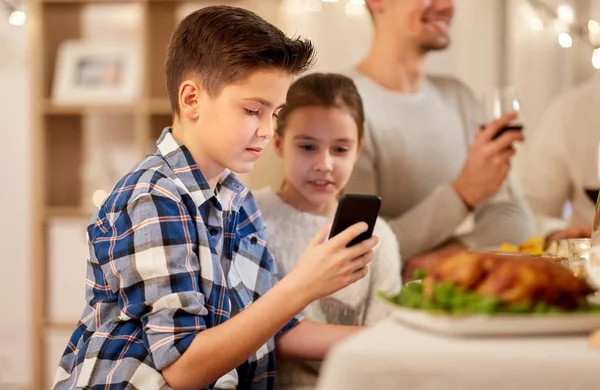 家族との夕食でスマート フォンを使用しての妹を持つ少年 — ストック写真