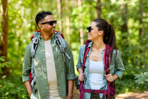 Pareja de razas mixtas con mochilas senderismo en el bosque — Foto de Stock