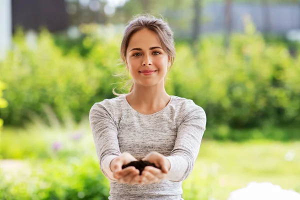 Young woman with handful of soil at summer garden — Stock Photo, Image