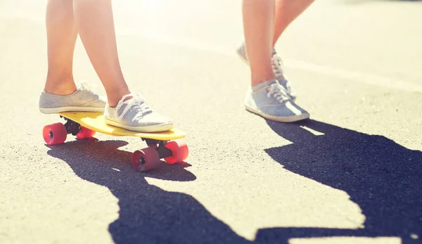 Pies de pareja adolescente montando monopatín en carretera — Foto de Stock