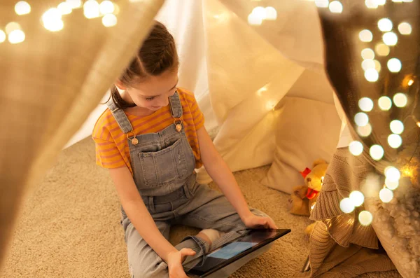 Evde çocuklar çadırda tablet pc ile küçük kız — Stok fotoğraf