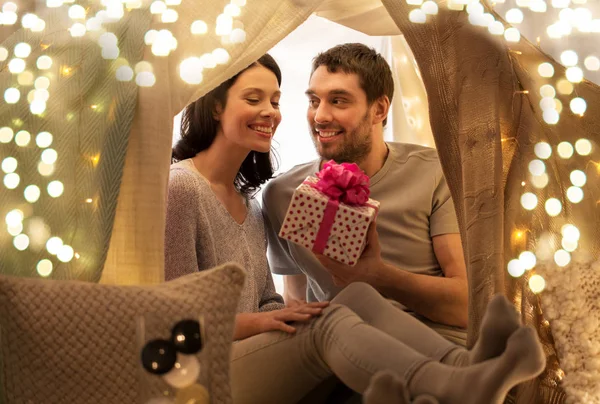 Šťastný pár s dárkovou krabicí v dětském stanu doma — Stock fotografie