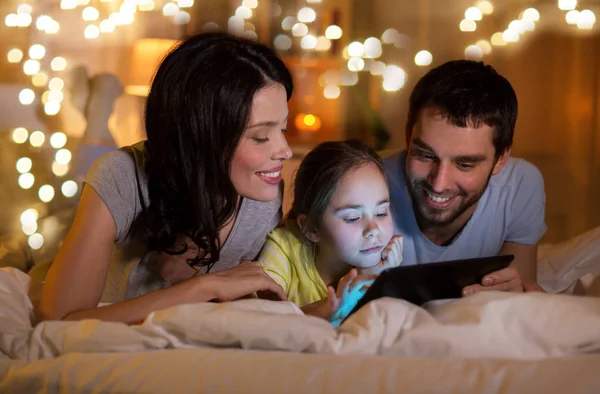 Familia con tableta pc en la cama por la noche en casa —  Fotos de Stock