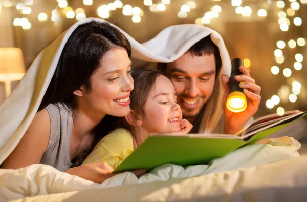 Libro de lectura familiar feliz en la cama por la noche en casa —  Fotos de Stock